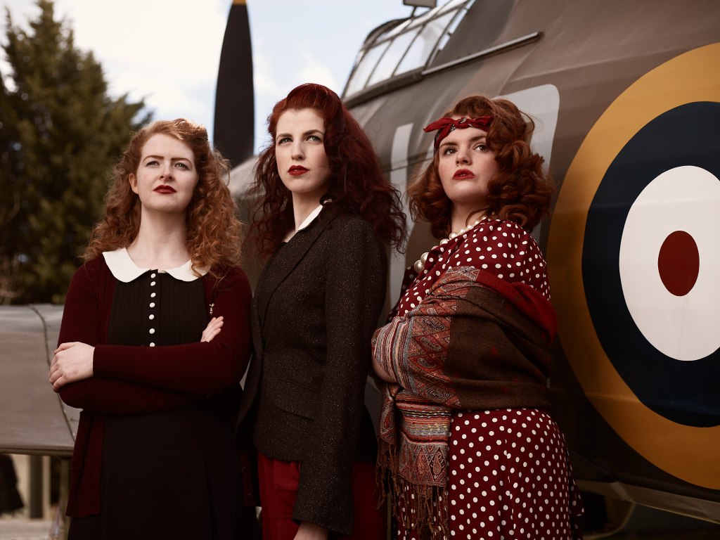 Cast members of Greyhounds in 1940s costumes, standing in front of a World War 2 Hurricane at Yorkshire Air Museum.